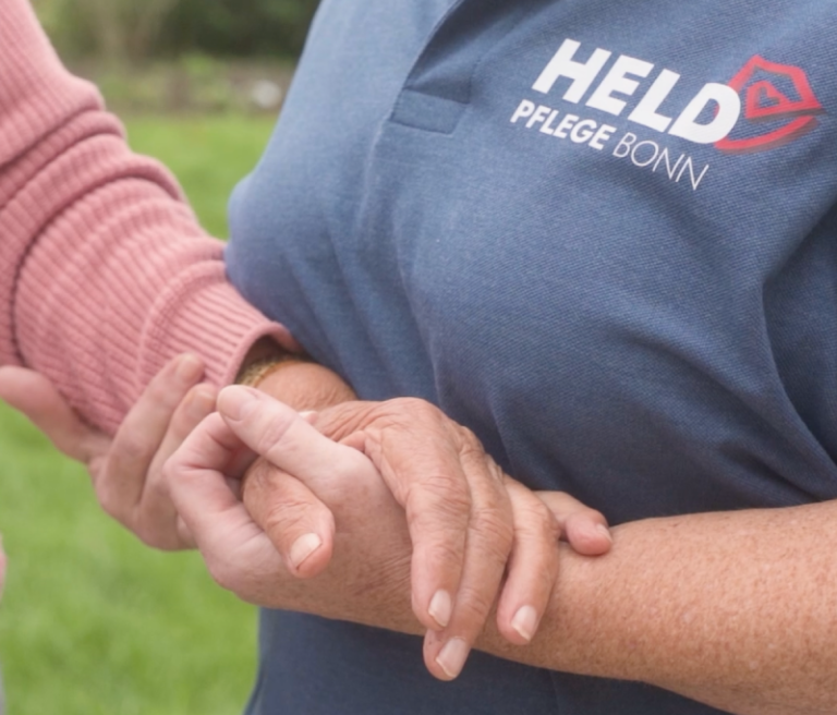 Pflegekraft von Held Pflege Bonn hält die Hand einer betreuten Person