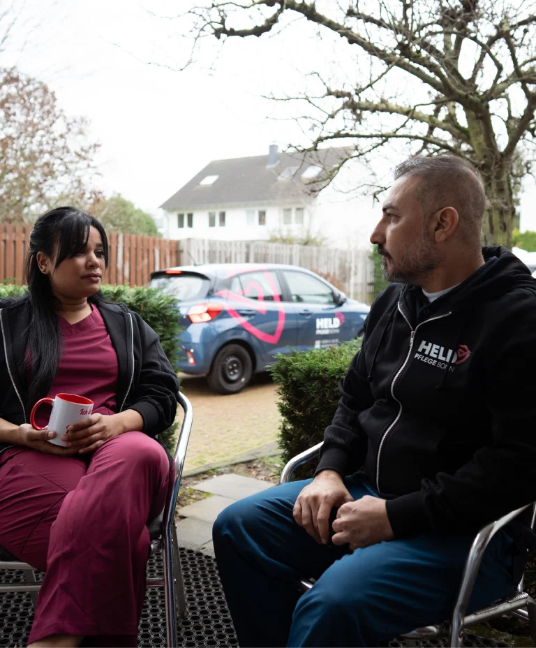 Pflegekraft von Held Pflege Bonn im einfühlsamen Gespräch mit einem Patienten im Wohnbereich.