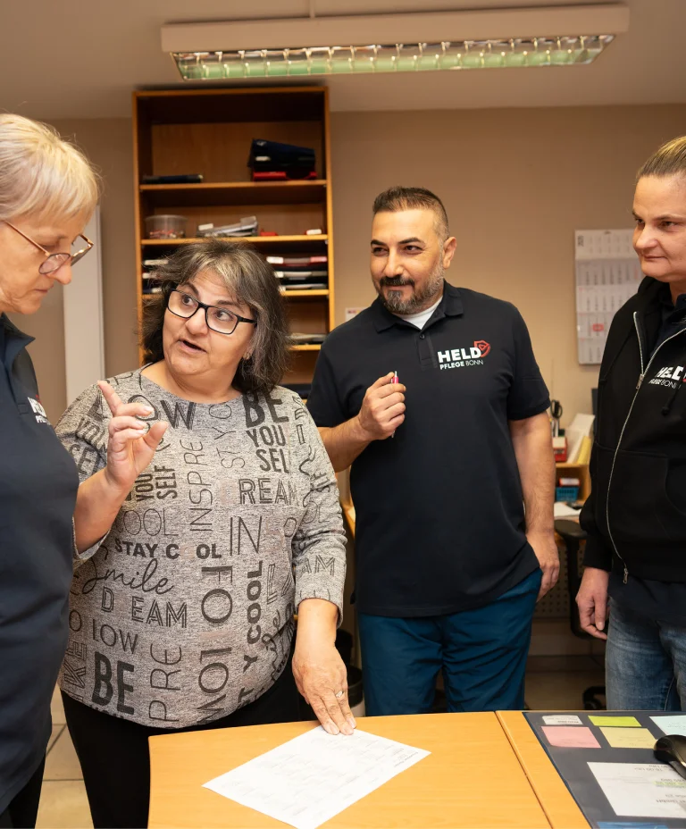Pflegekräfte von Held Pflege Bonn im freundlichen Gespräch im Büro.