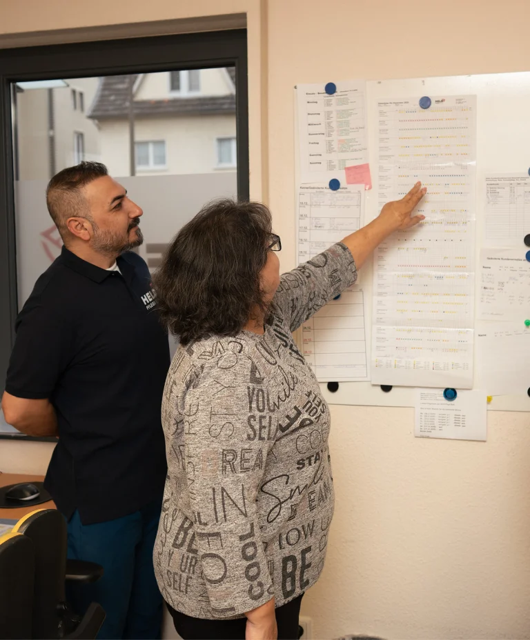 Pflegemitarbeiter von Held Pflege Bonn erklären Abläufe anhand eines Plans im Büro.