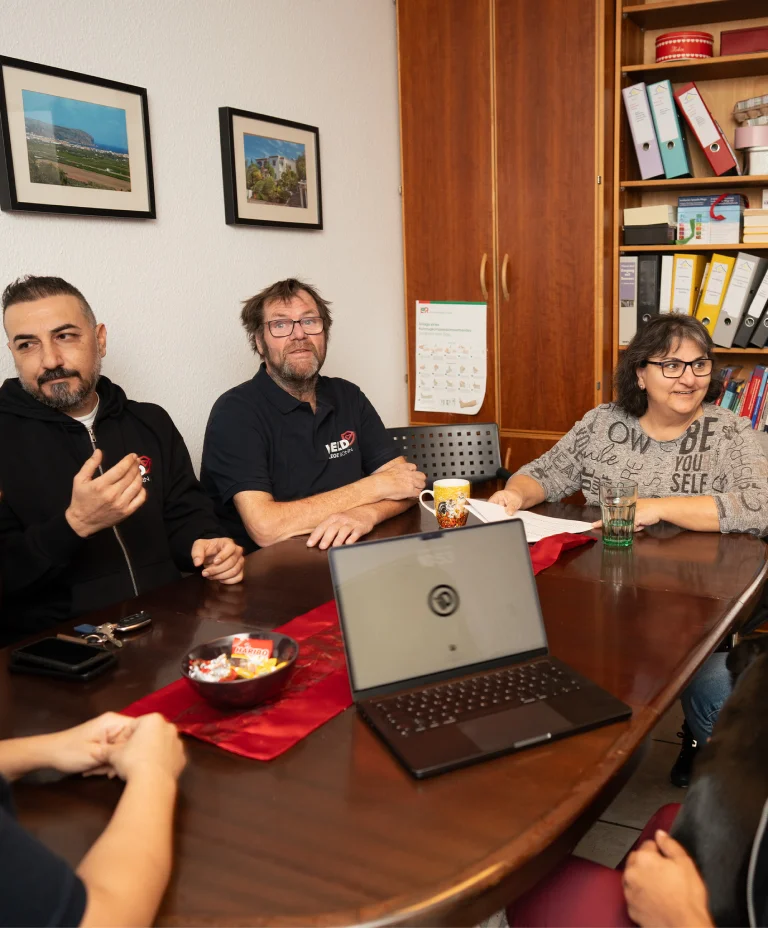 Pflegekräfte von Held Pflege Bonn bei einer internen Besprechung mit Laptop im Büro.